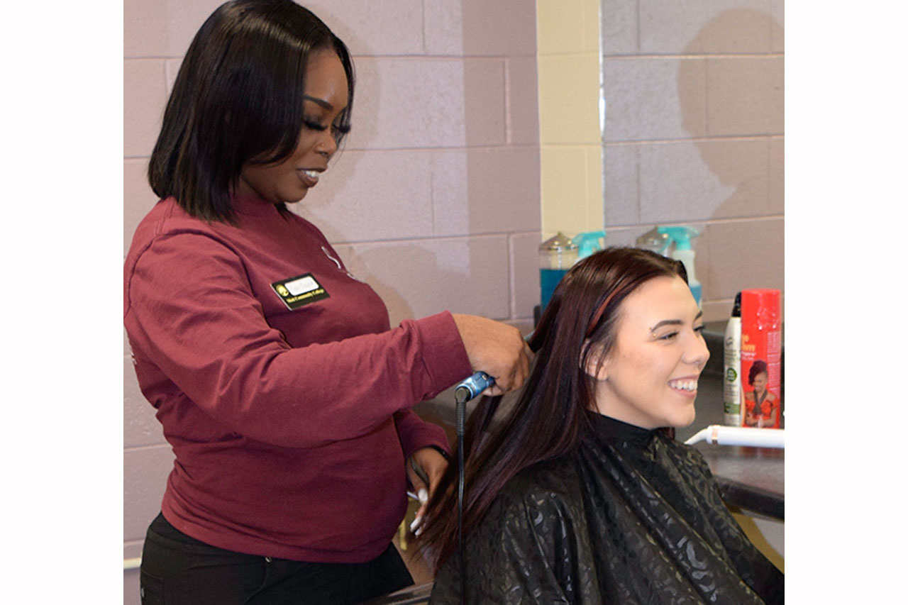 Student using flat iron on patron