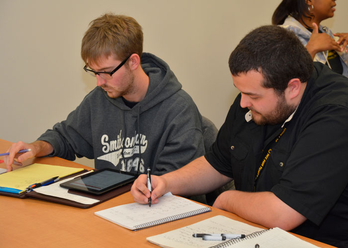 two students taking notes in class