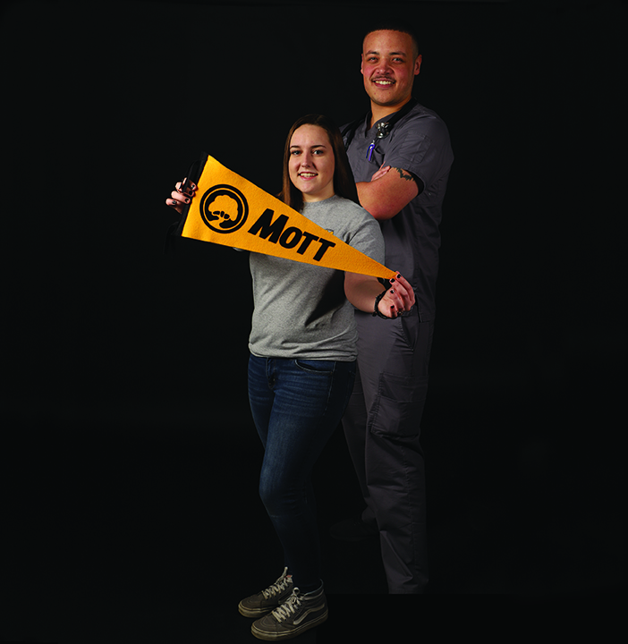 two college students holding Mott College pendant