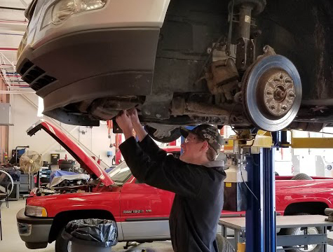 Automotive garage student working under raised car